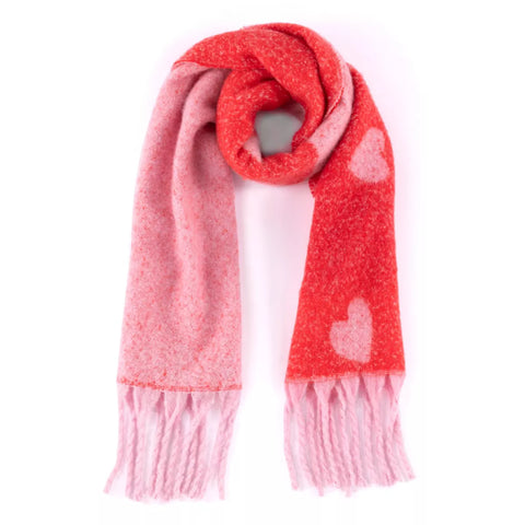 Image shows a pink and red blanket scarf with fringe and hearts pattern. 